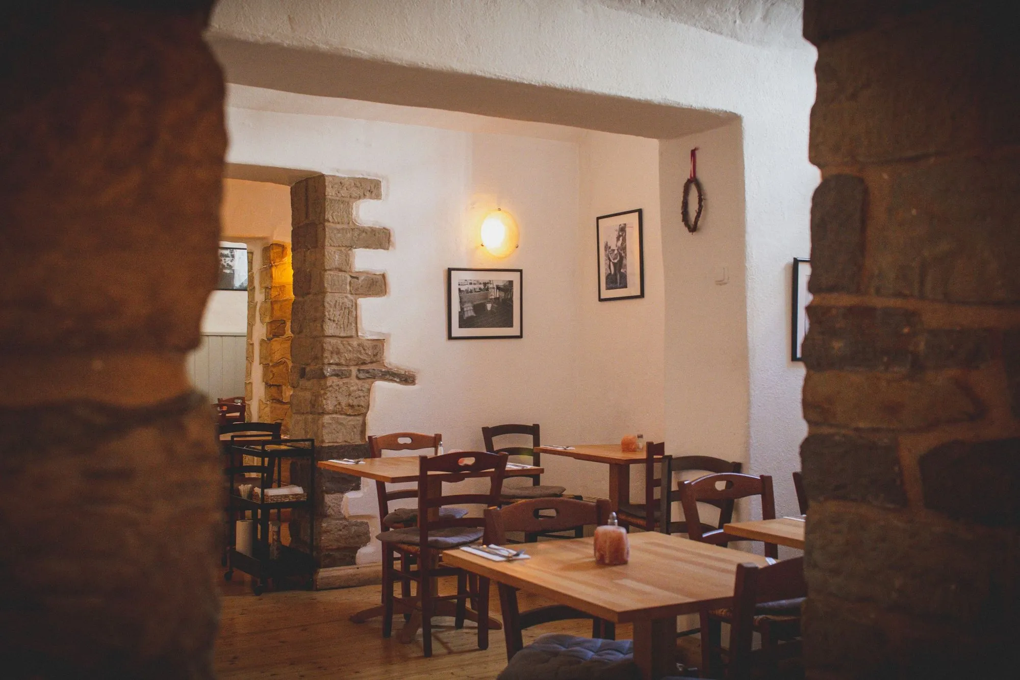 The dining room through a stone archway, timber tables under a lime-washed wall