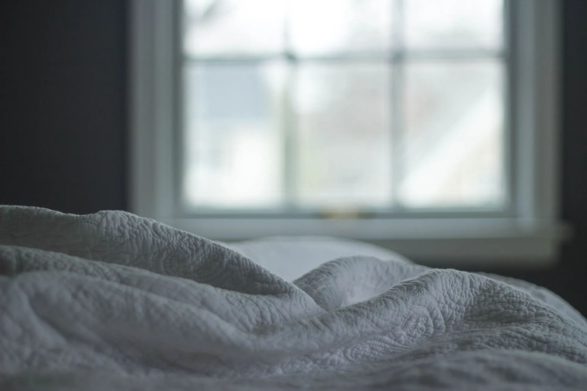Quilted bedcover in soft light from a window