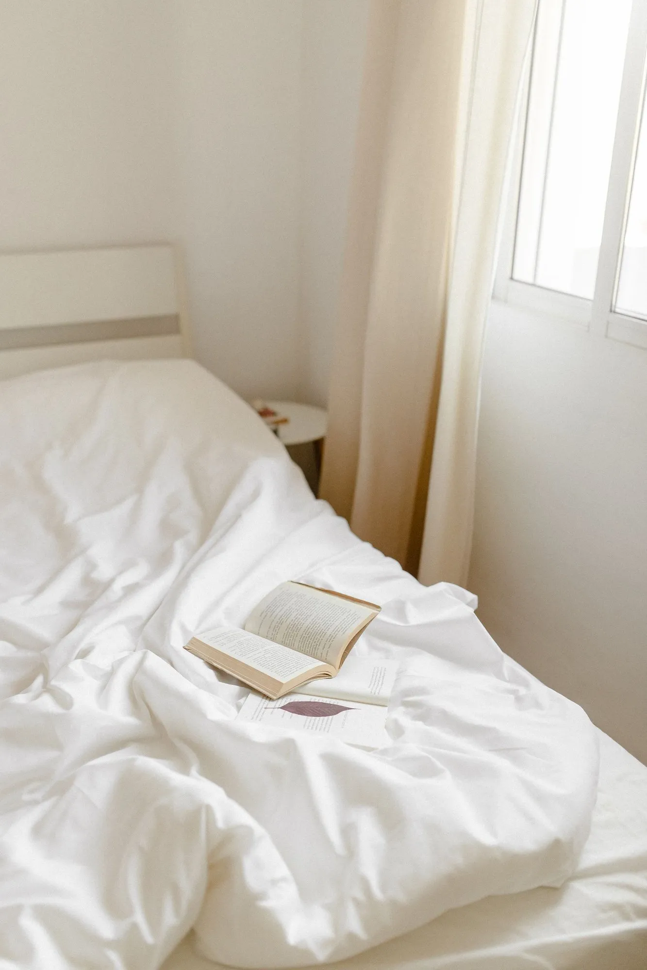 An open book on the rumpled bed in the Snug, lit from the side window